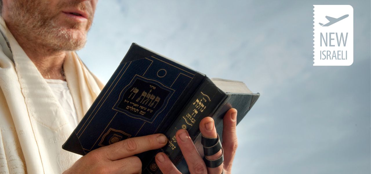 Мужчина в белом талите читает праздничный молитвенник Махзор на Йом-Кипур